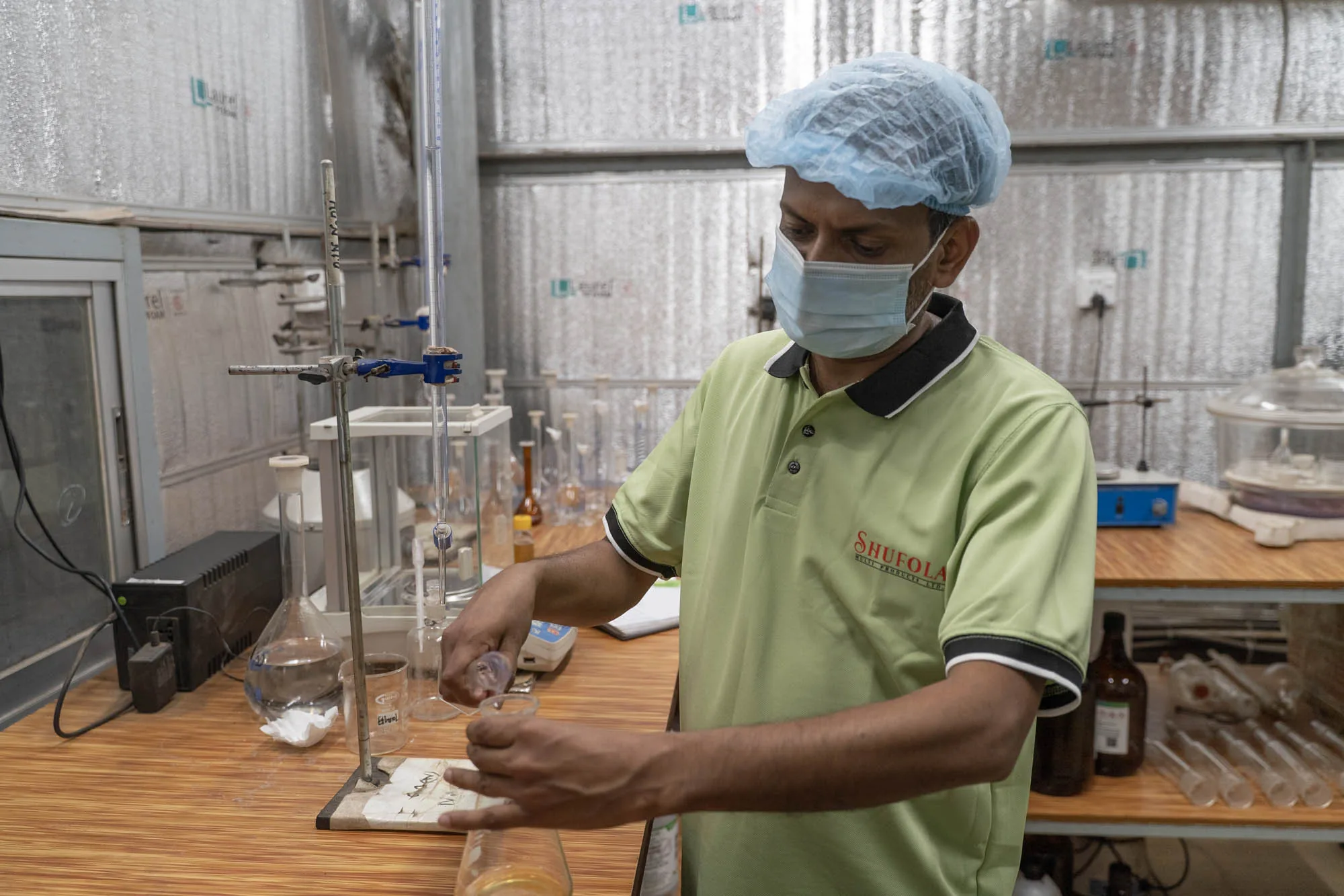 Quality-control technician with titration setup in the Ullapara laboratory