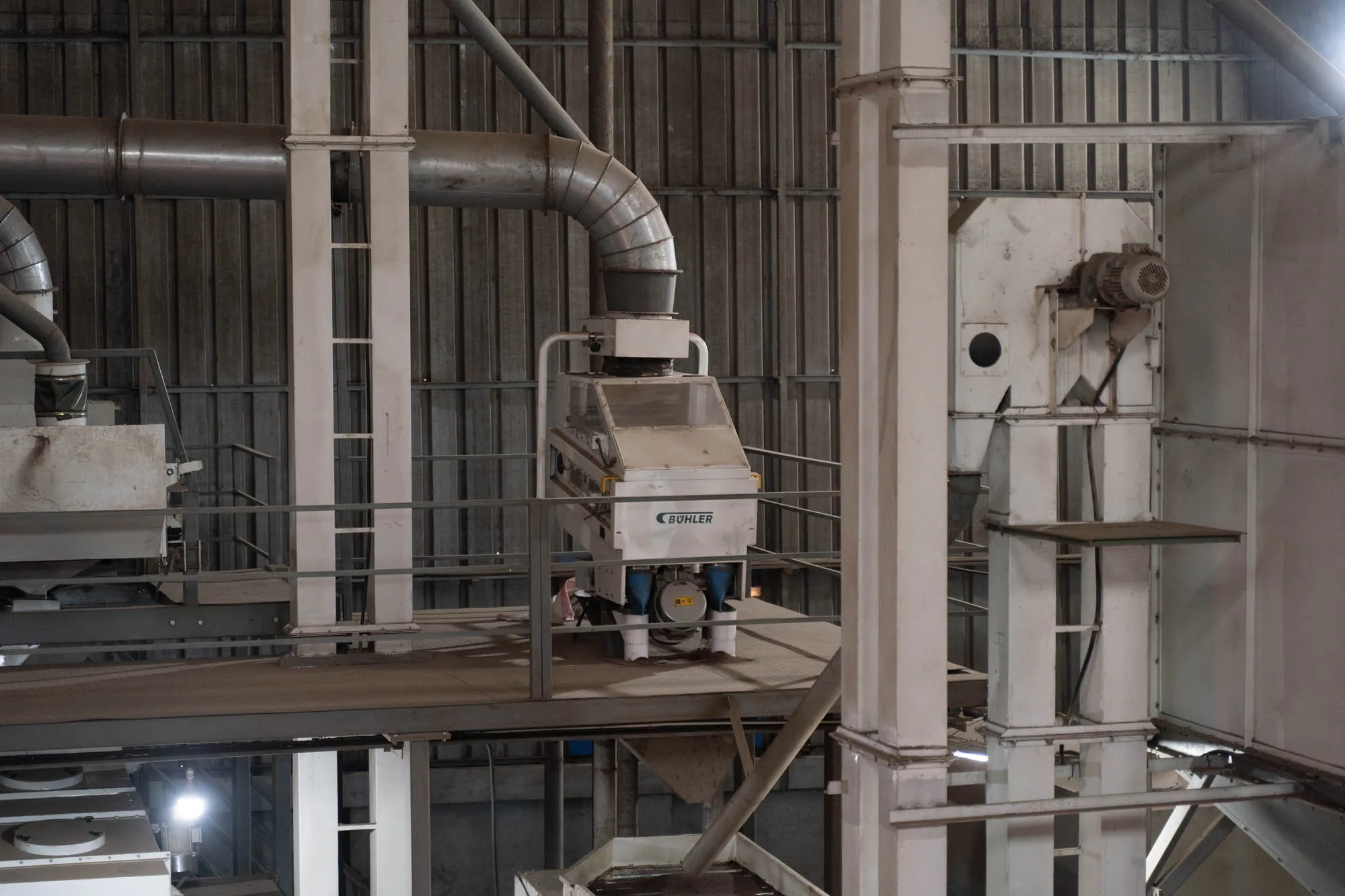 Bühler-branded seed-cleaning machine on the raised catwalk inside the Ullapara facility
